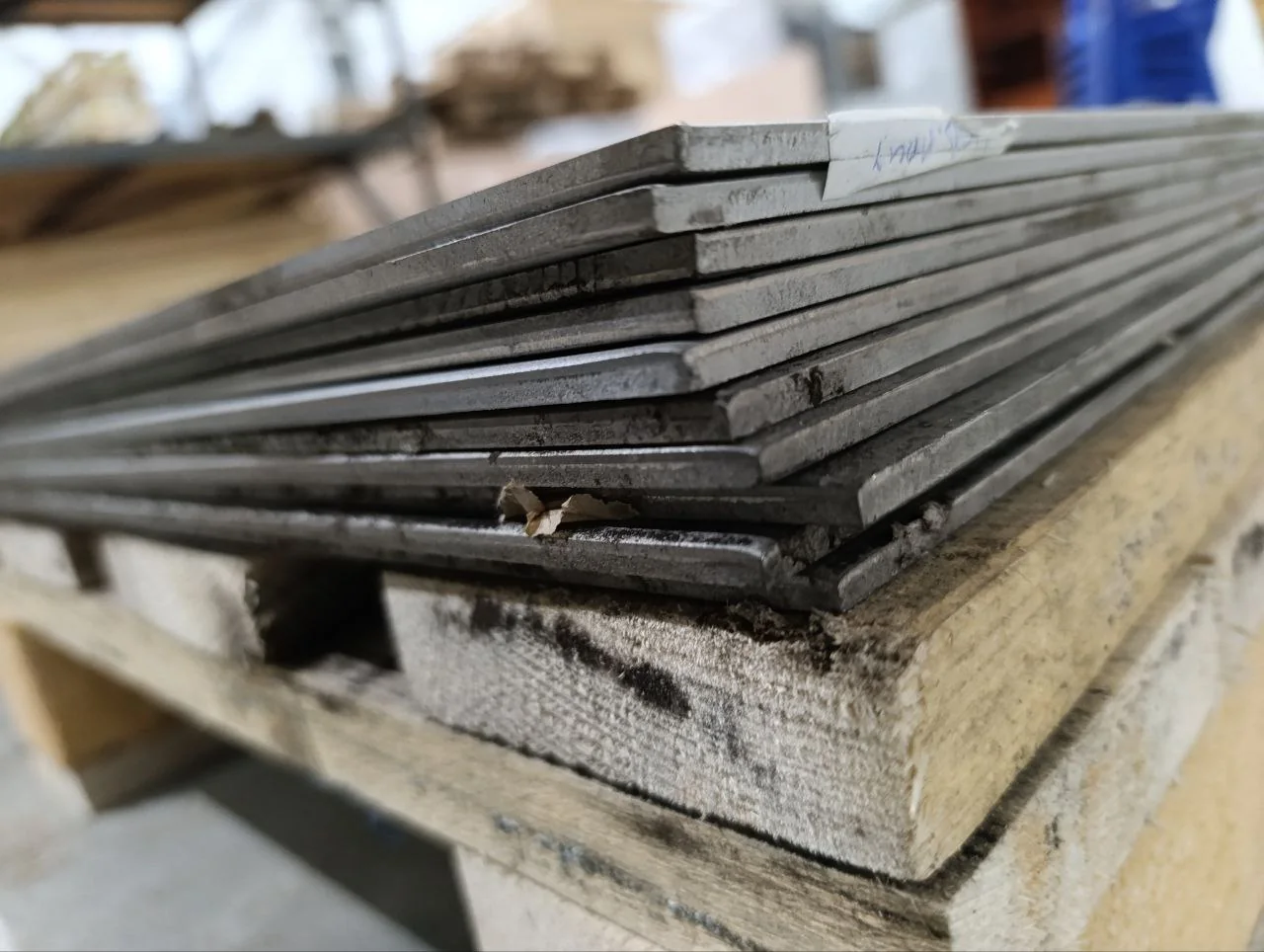 Heavy industrial metal plates stacked on a workshop pallet
