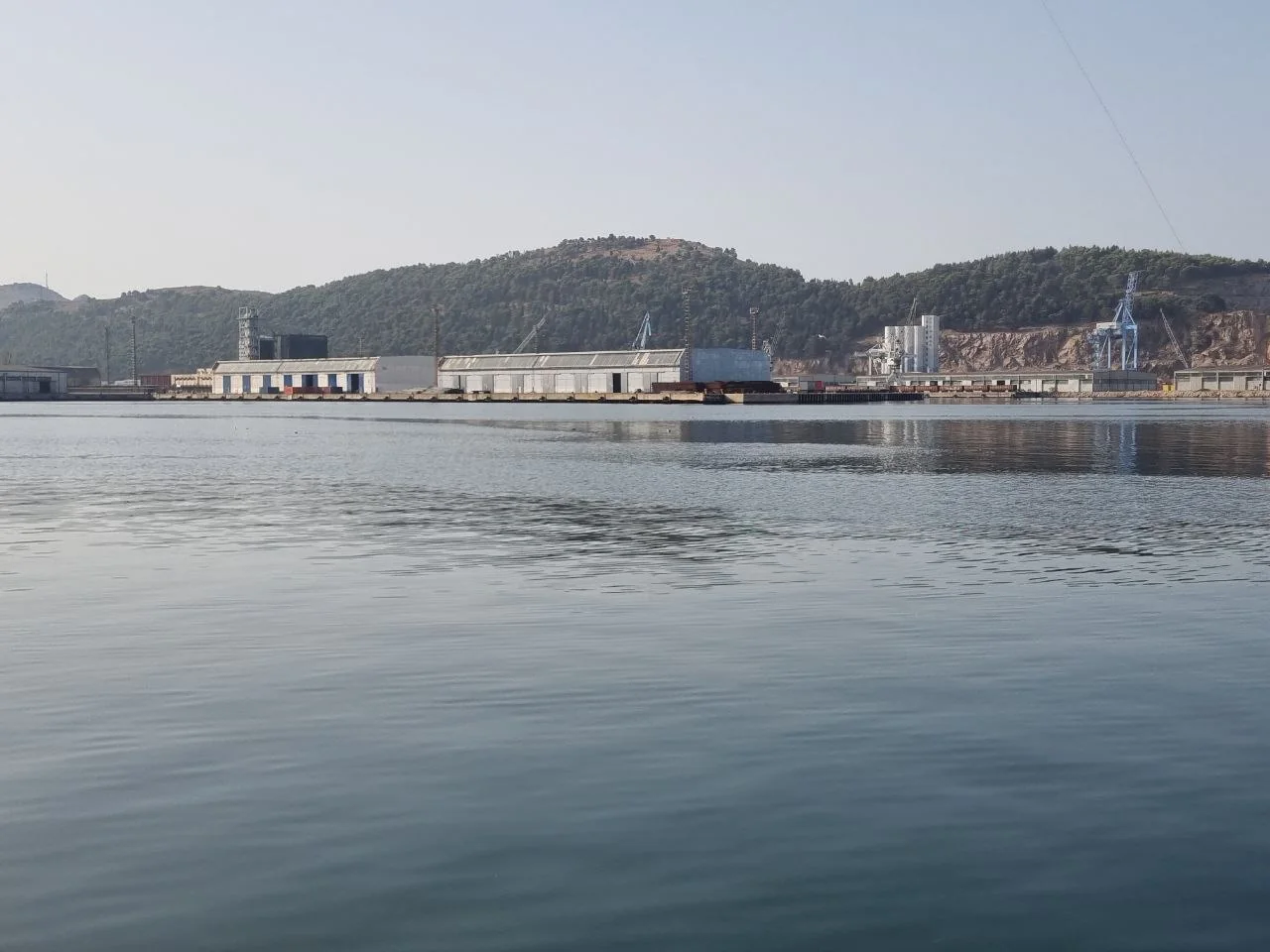 Maritime industrial terminal viewed across calm coastal water